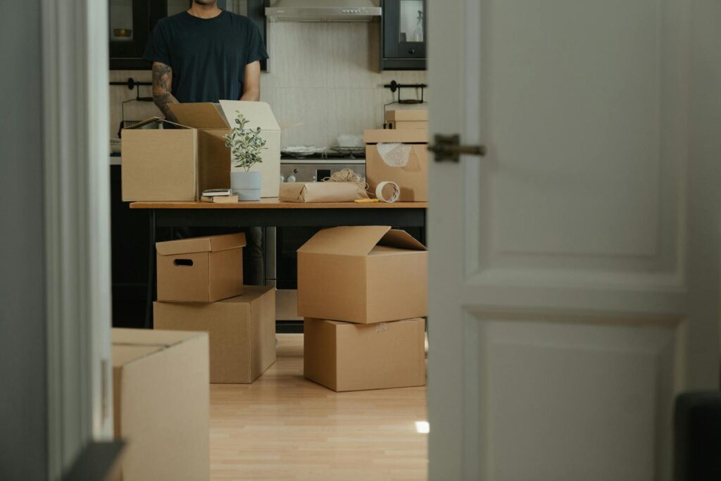 Person unpacking cardboard boxes in a modern kitchen during relocation.