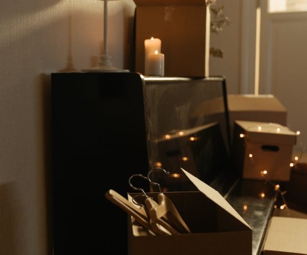 A warm and cozy room with cardboard boxes, a piano, and ambient lighting creating a peaceful atmosphere.
